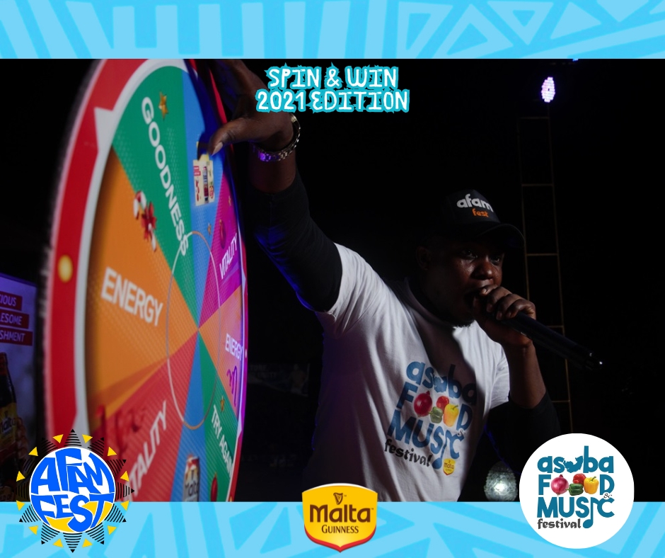 A festival-goer spins the prize wheel at the AFAM FEST Spin & Win booth, surrounded by cheering fans