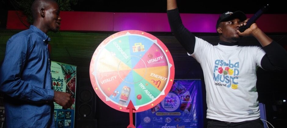 A contestant spinning the wheel while an event host announces the prize at AFAM FEST. Description: The Spin & Win Booth is always packed with festival-goers hoping to land on amazing rewards! Don’t miss your turn at AFAM FEST 2025.